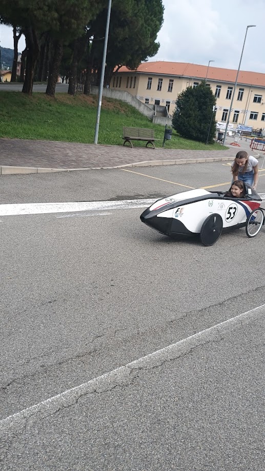 Due persone accanto al velomobile bianco numero 53 nell’area della Festa dello Sport
