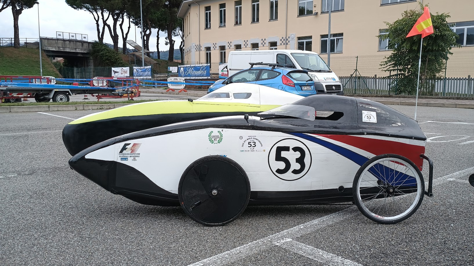 Il velomobile bianco numero 53 accanto a un velomobile nero e giallo nell’area della Festa dello Sport