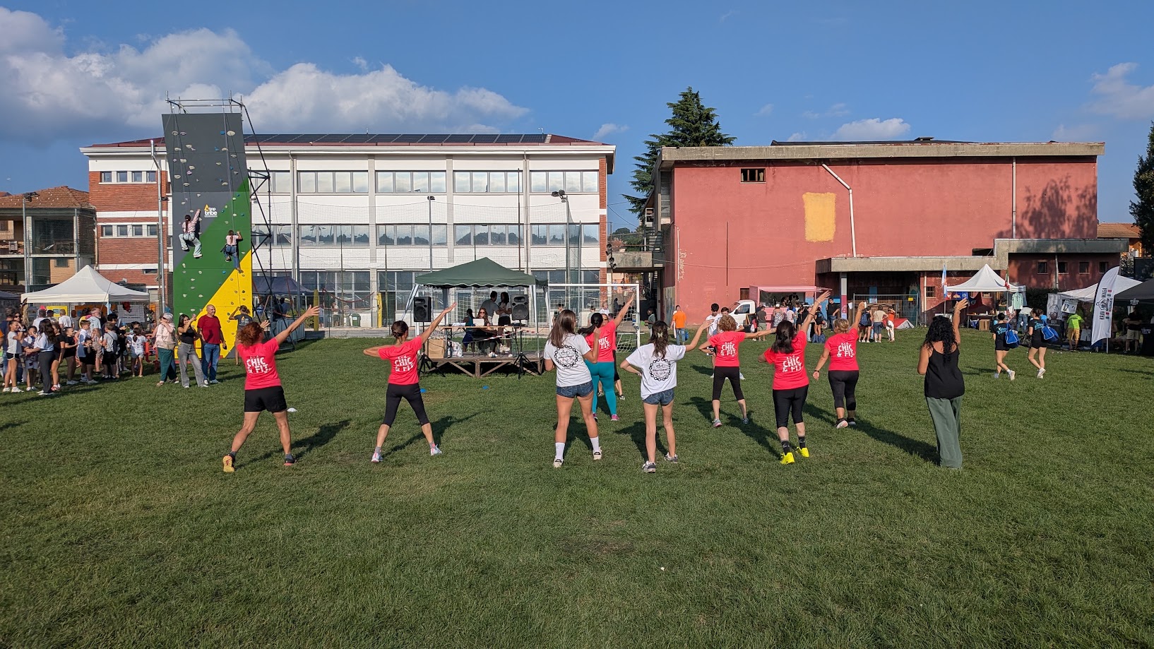 Un gruppo svolge un’attività sportiva sul prato, con gli stand della Festa dello Sport sullo sfondo